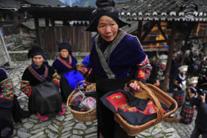 An ethnic Miao woman carries baskets of hand embroideries to show guests, on the first day of the Guzang Festival in Leishan county, where most of the Miao ethnic group live, southeast Guizhou province, November 26, 2012. Guzang Festival, during which the Miao ethnic minority people commemorate their ancestors once every 13 years, is one of the biggest traditional festivals for the Miao ethnic minority people. "Gu" literally means "drum", and "zang" means "to bury". The complicated rites which take three years to complete consist of a series of great ceremonies, including the Zhaolong (inviting the dragon), Xinggu (awakening the drum), Yinggu (welcoming the drum), Shenniu (inspecting the cattle), and the white drum ritual, which is a significant sacrifice marking the end of the festival. The Miao believe wooden drums made of maple trees are where their ancestors' souls rest, so they gather under the holy maple and communicate with their ancestors through drumming and dancing, local media reported. Picture taken November 26, 2012. REUTERS/Sheng Li (CHINA - Tags: SOCIETY ANNIVERSARY)
